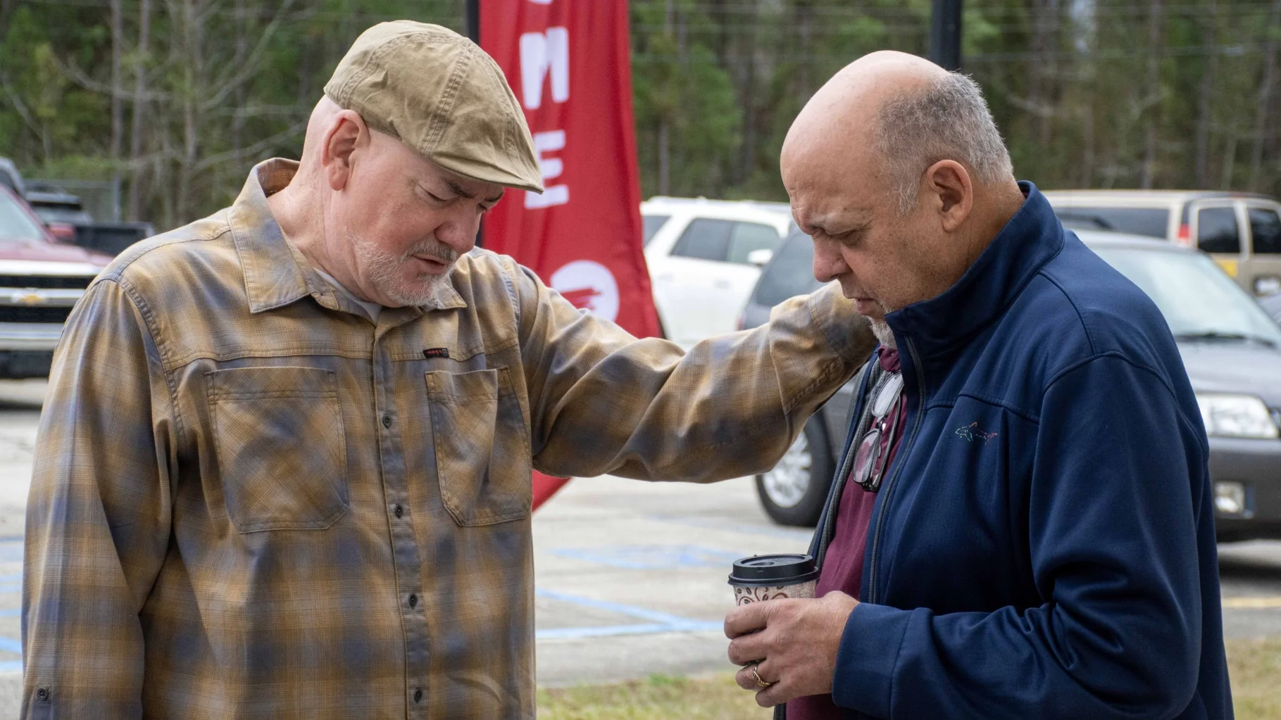 Man praying with his hand on a friend’s shoulder